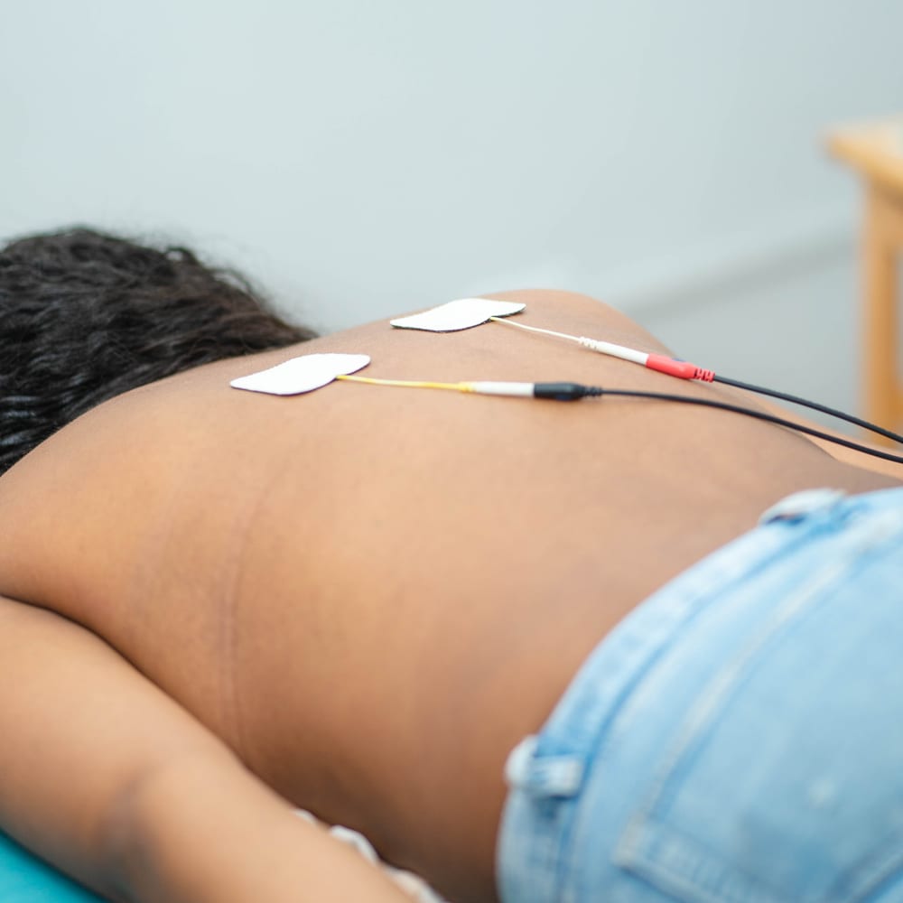 Electrodos de electroterapia colocados en la espalda de una paciente