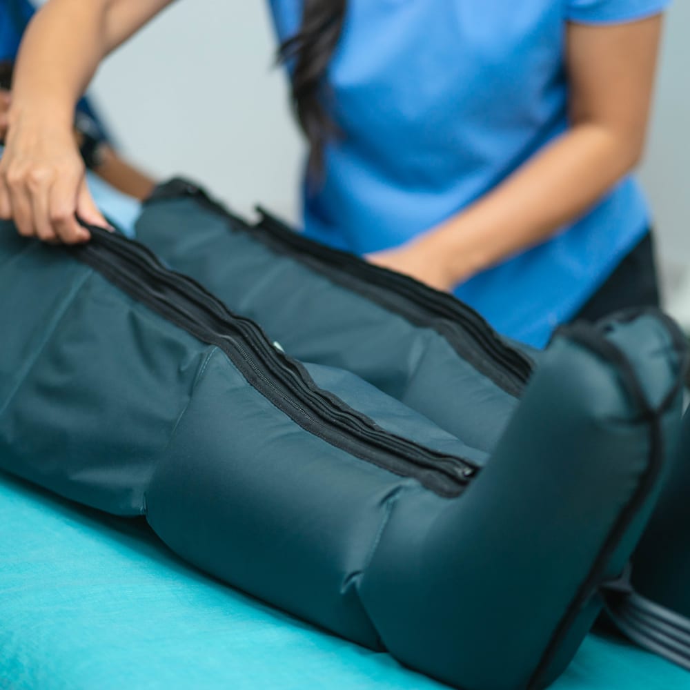 La fisioterapeuta coloca las botas de presoterapia a un paciente